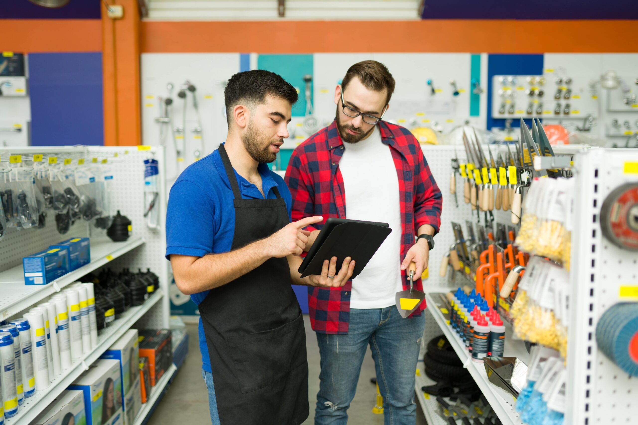 An employee looking for a product with a customer at the hardware store uses his wireless tablet that is powered by Kinetic Business fiber-based internet.