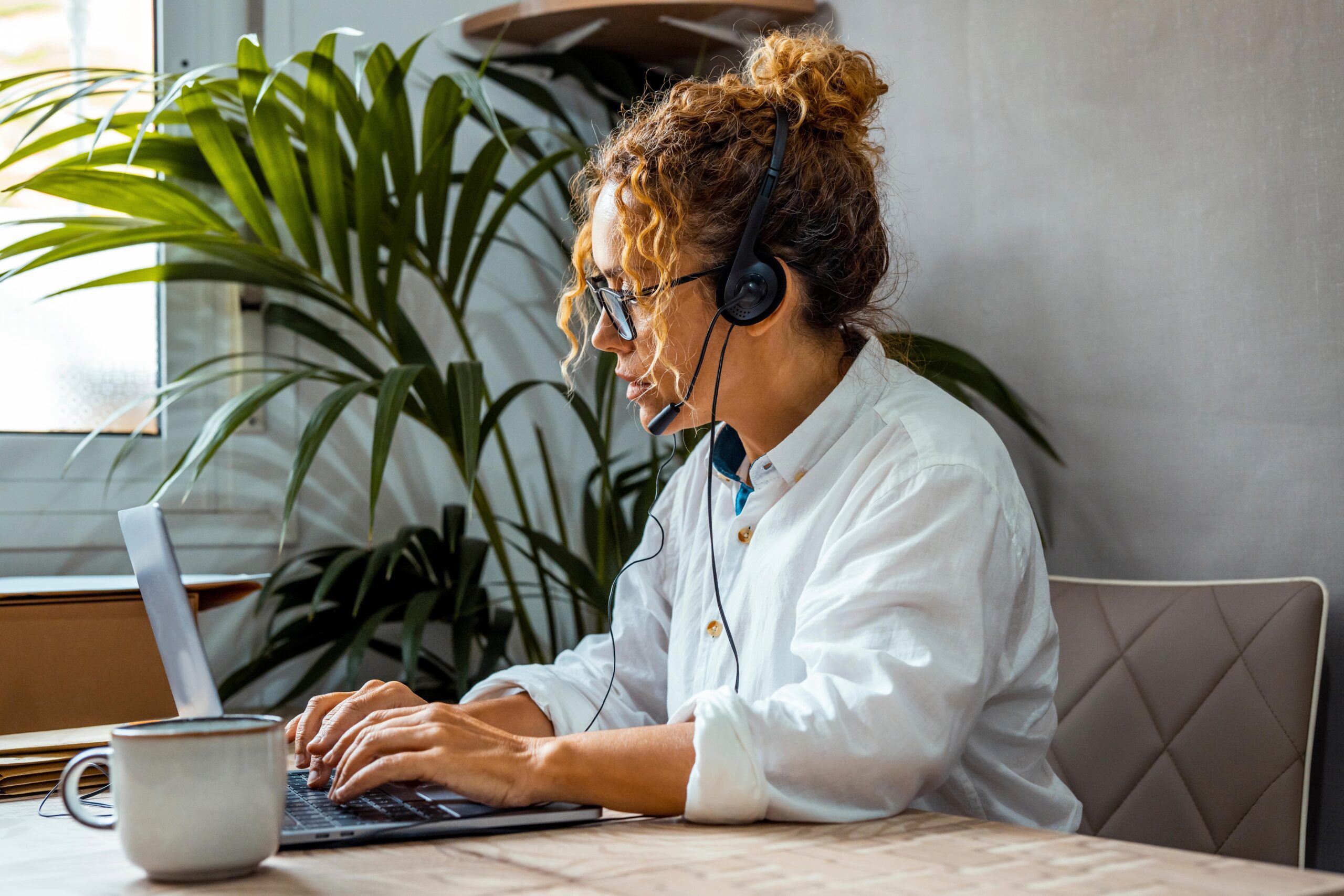 Worker wearing a headset sits at her desk using a laptop for a voice and video call with clients powered by Kinetic Business