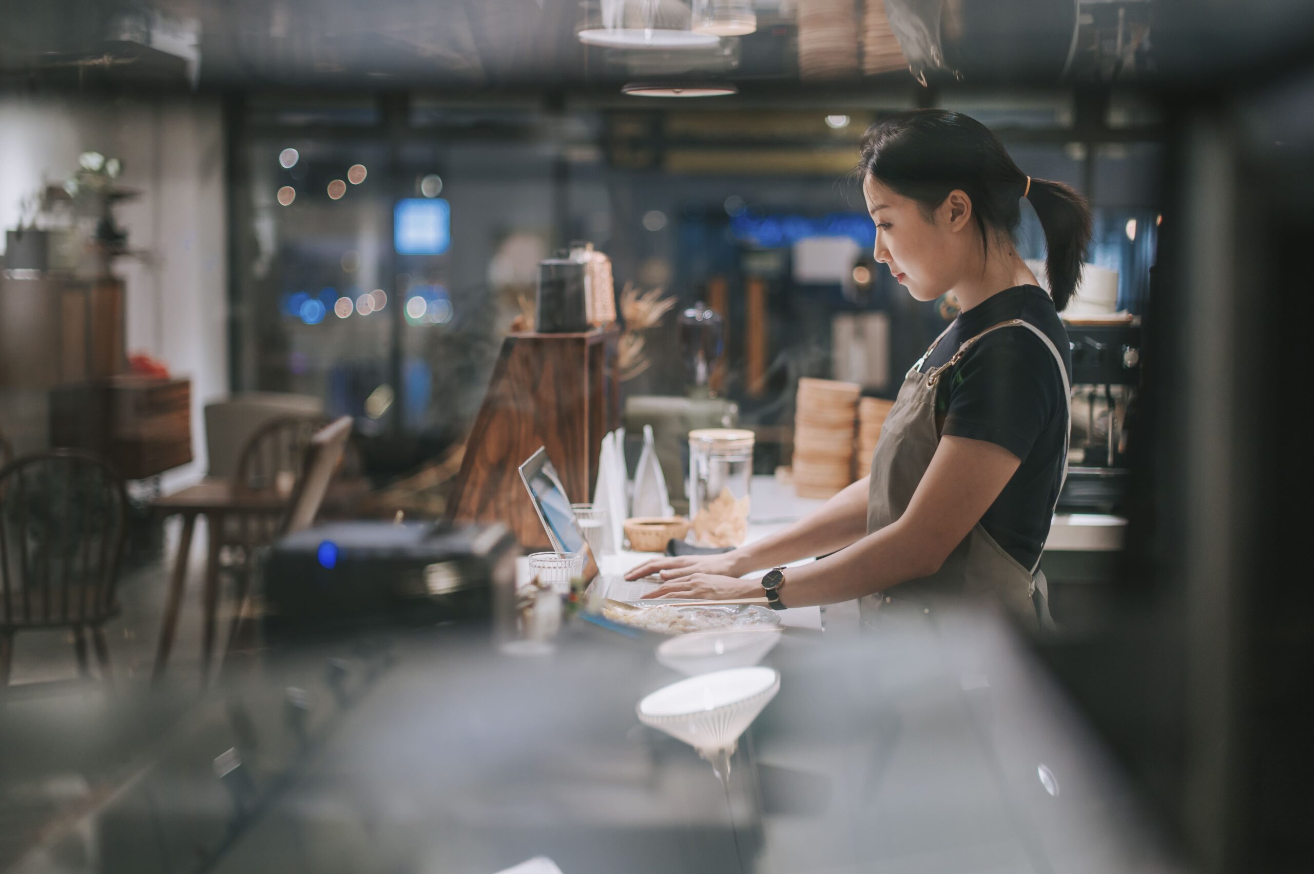 Female barista uses laptop at coffee bar counter connected to the internet by high speed Kinetic Business internet service