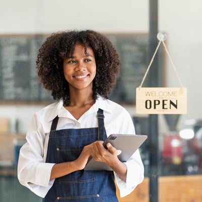 Female retail worker next to open sign.