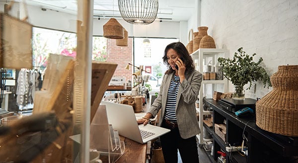 Businesswoman using internet and technology to run a local retail shop while using the phone.
